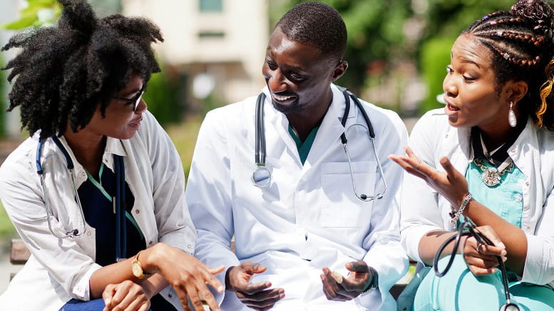 three medical students sitting outside smiling and talking