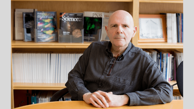 Samuel Stupp, Board of Trustees Professor of Materials Science and Engineering, Chemistry, Medicine, and Biomedical Engineering, is pictured seated in front of a bookshelf. He wears a dark gray collared shirt.